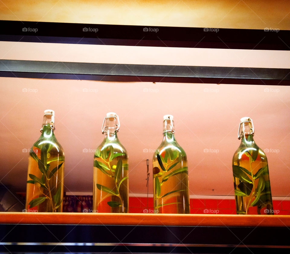 Four bottles of oil in which branches with olives