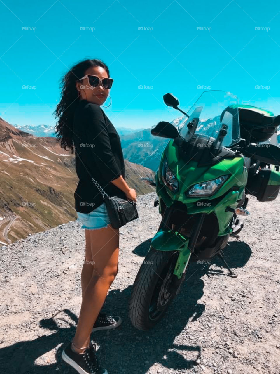 Young woman and motorbike on mountain road trip