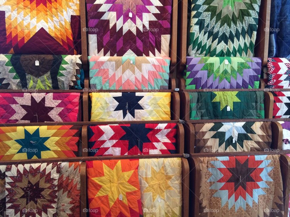 Beautiful, colorful, handmade quilts displayed on racks