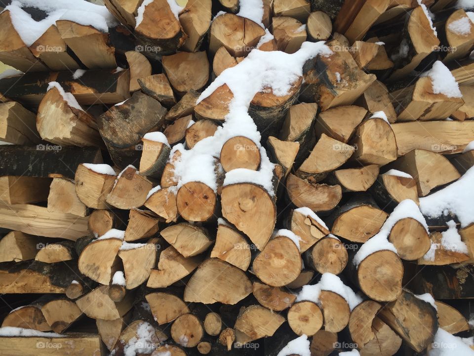 Pile of cut firewoods covered in snow