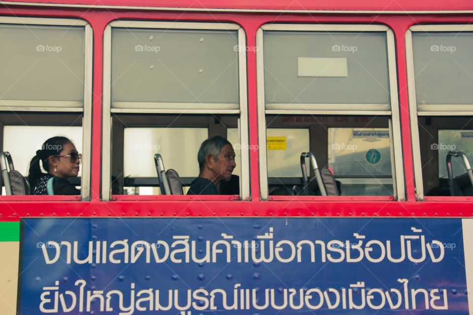 a grandfather sitting on a bus in the city of Bangkok