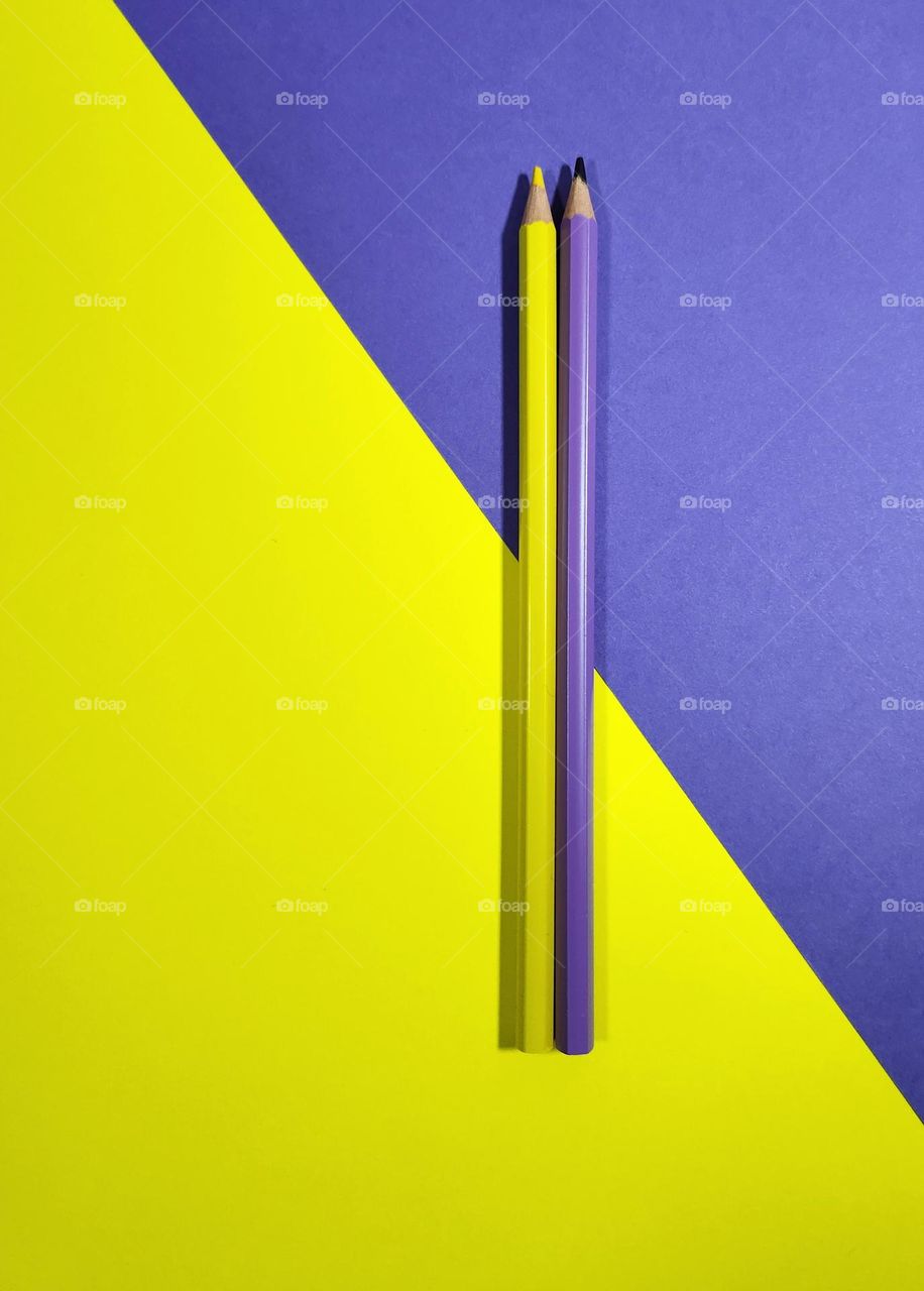Yellow and purple complementary colours flatlay composed of yellow and purple papers and pencils
