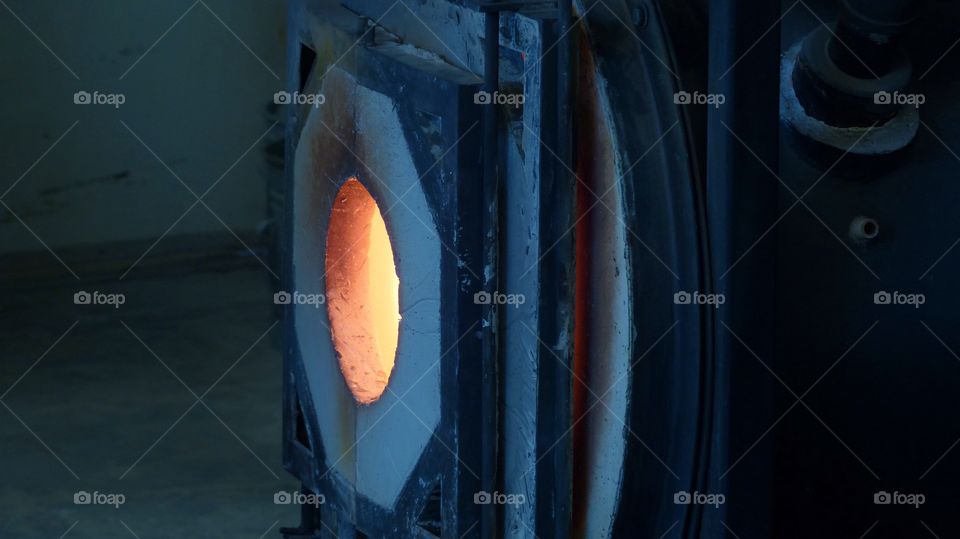 Black glass melting furnace with orange glow from heat