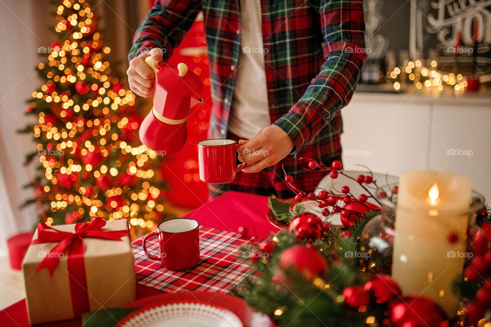 Festive winter cozy kitchen interior with garlands, decorations and gifts.  Christmas dinner at the decorated table.