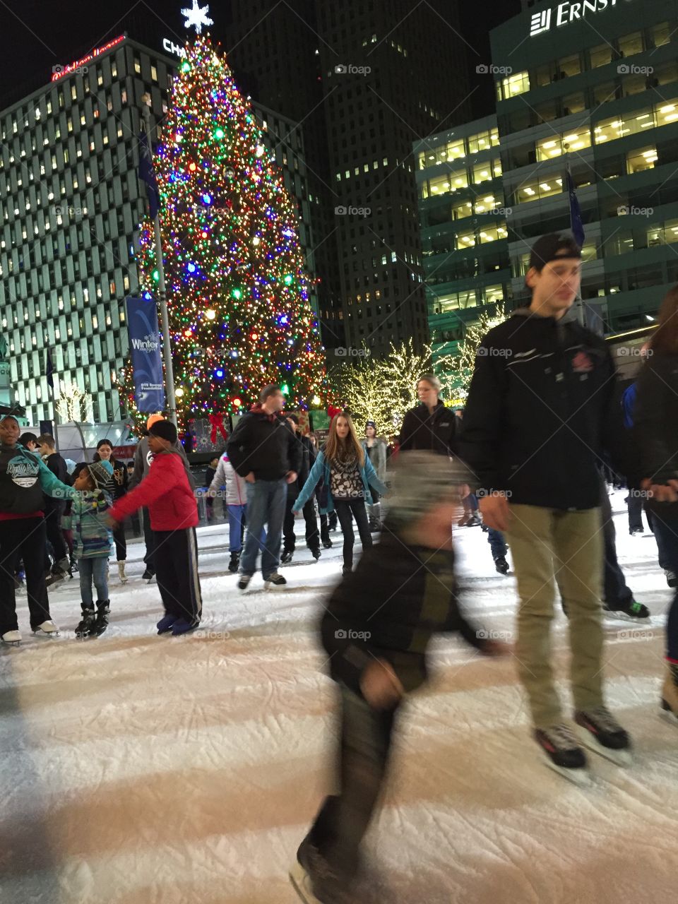 People enjoying ice skating with illuminated christmas tree