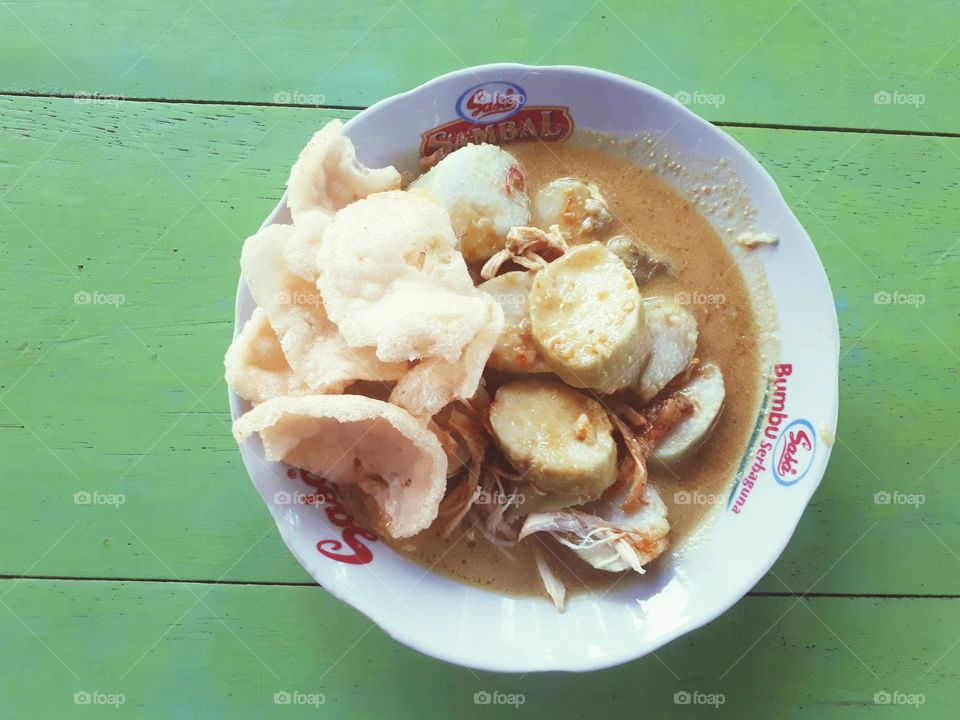 Lontong opor is served on a white round plate with the Sasa brand