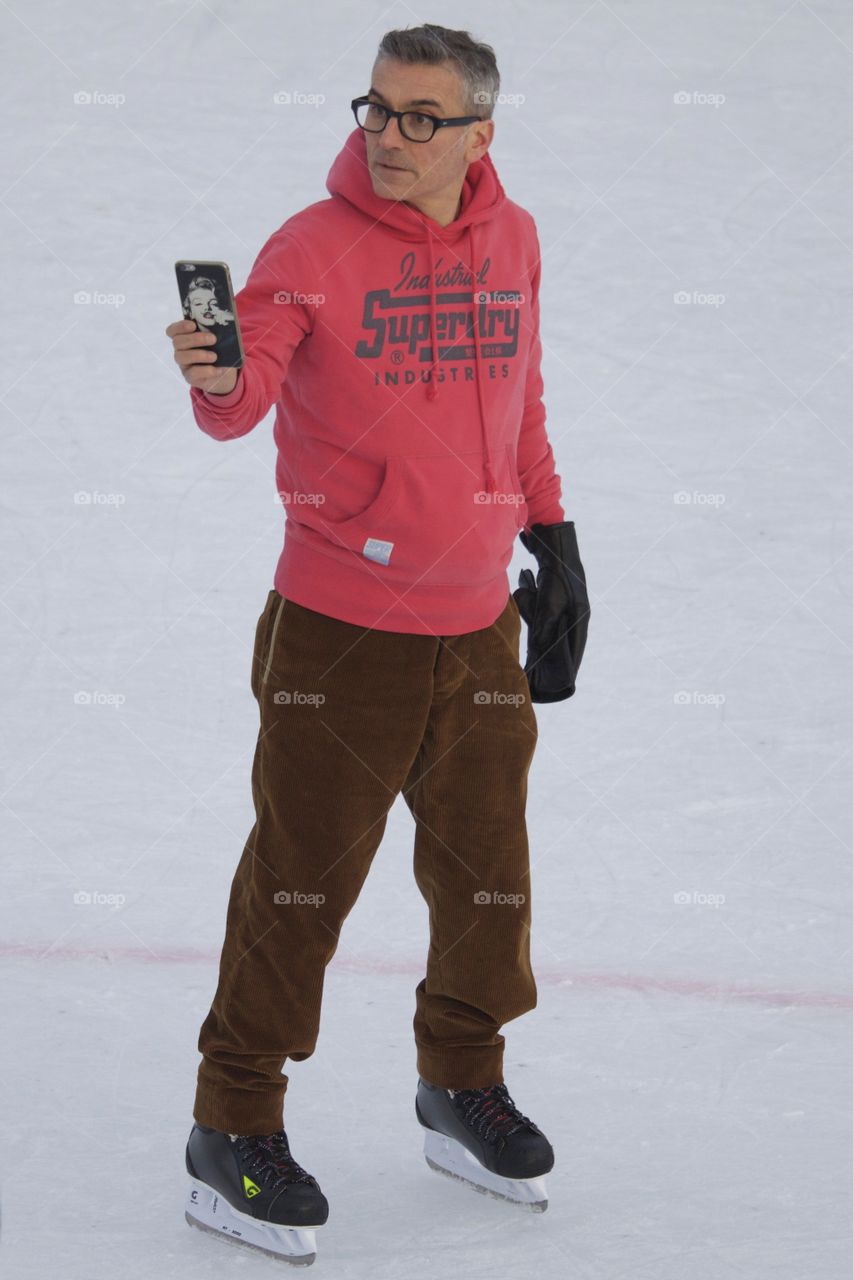 Man With Smartphone On Ice Rink