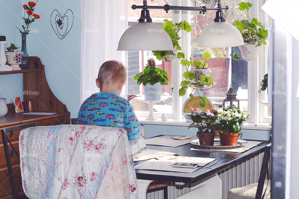 Boy sitting on the table. Playing at the table