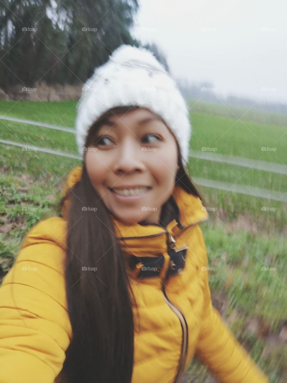 Moving run blur young woman coat cold winter filed nature selfie grass white hat yellow happy smile