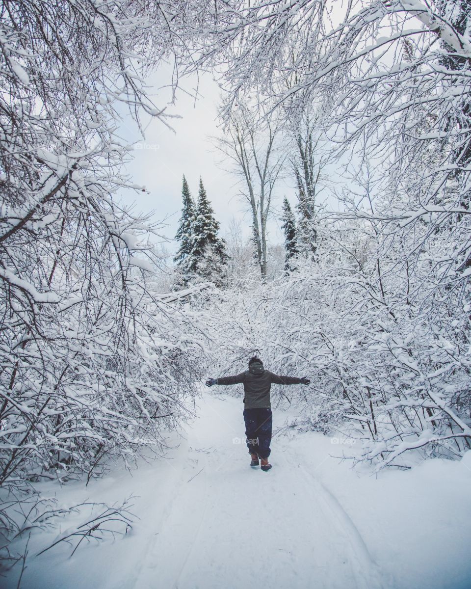 A young man through a massive snowy forest on a beautiful hiking trail
