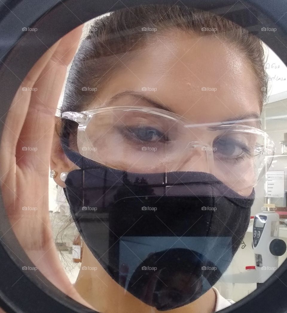 Clic descontraído em laboratório, pose segurando a lente de leitura de umidade e óleo. Olhar através da lente