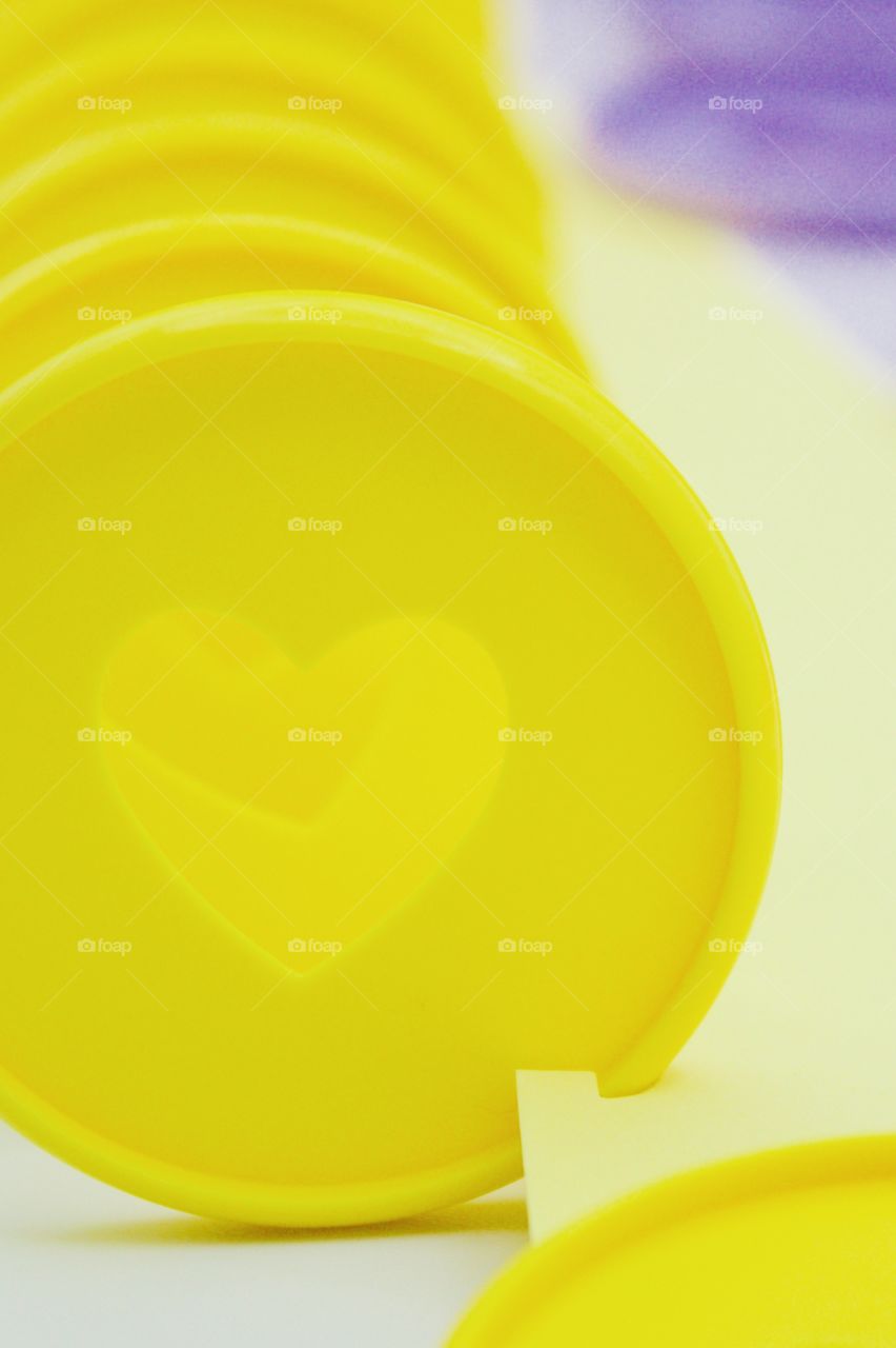 Closeup of yellow discbound disc with heart-shaped cut-out  for discbound planner against white background