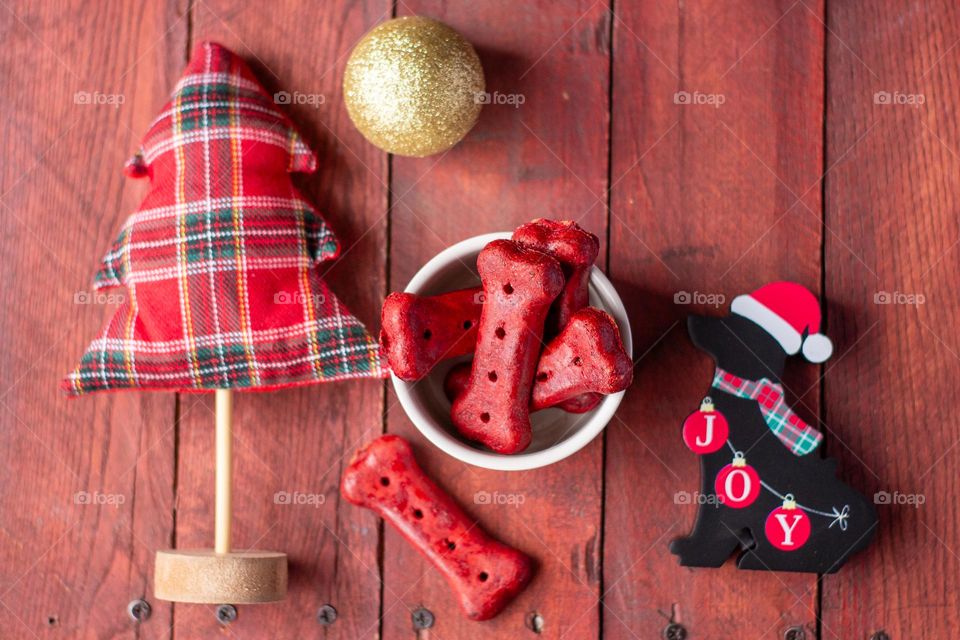 Holiday scene with a decorative dog and a bowl of red colored dog treats along with a tiny tree and ornament