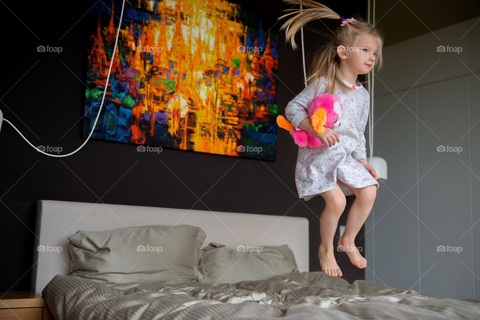 Girl jumping on bed in family bedroom