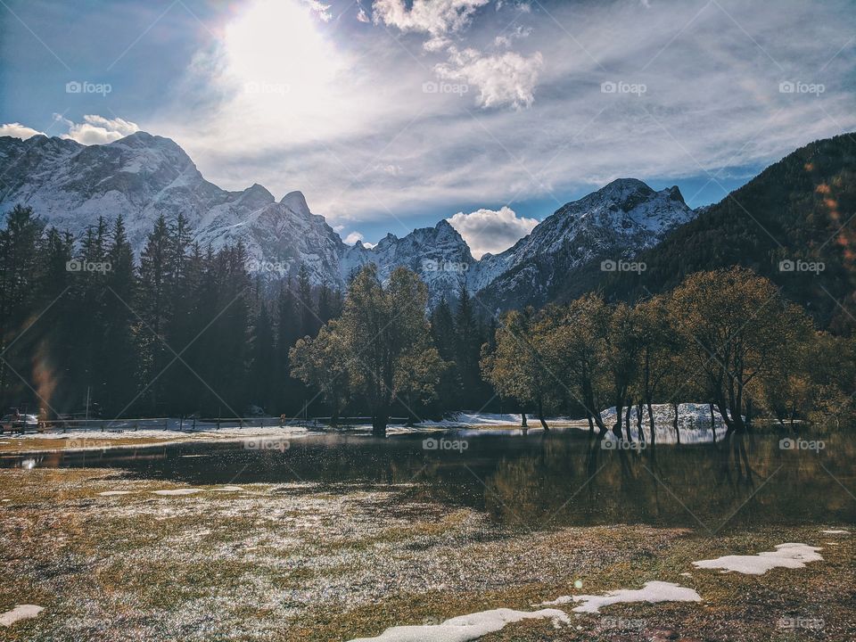 View of the autumn snow-capped mountain peaks against the backdrop of a transparent Italian lake.