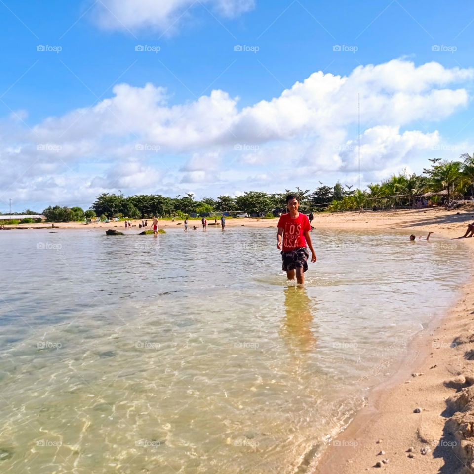 a young boy is standing on the beach in the summer