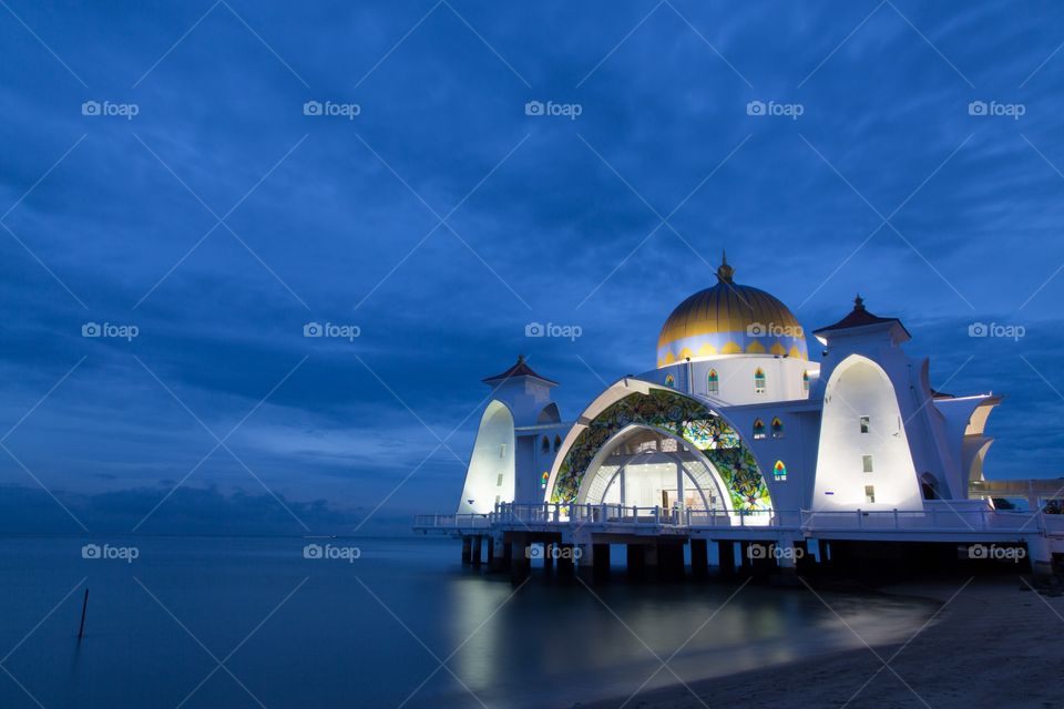 Night view of a mosque. Dreamy photo of a well lit mosque under the cloudy evening sky next to a sea. Malacca straits mosque. Masjid Selat Melak