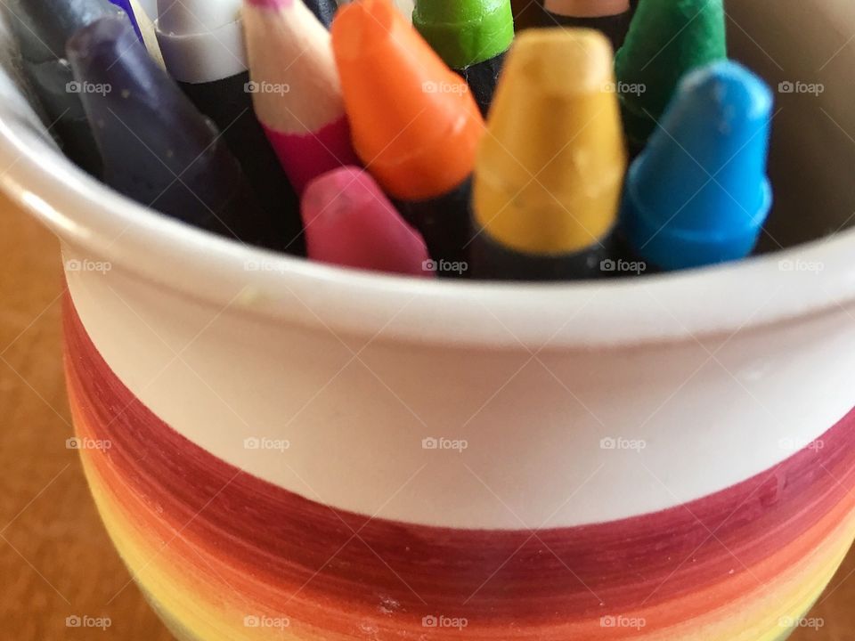 Art supplies of colourful crayons and pencils in rainbow ceramic pottery