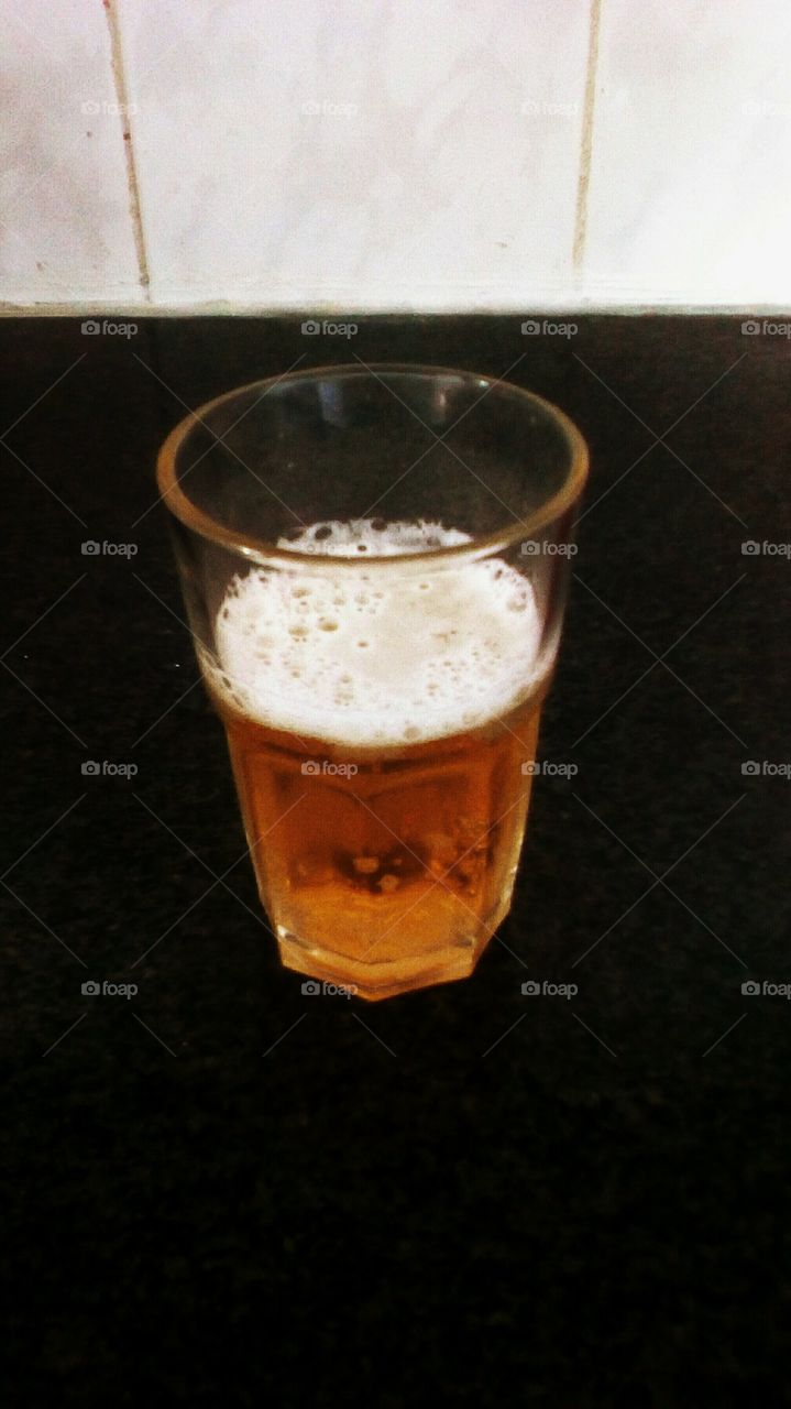 Glass with cold frothy beer on black
backround