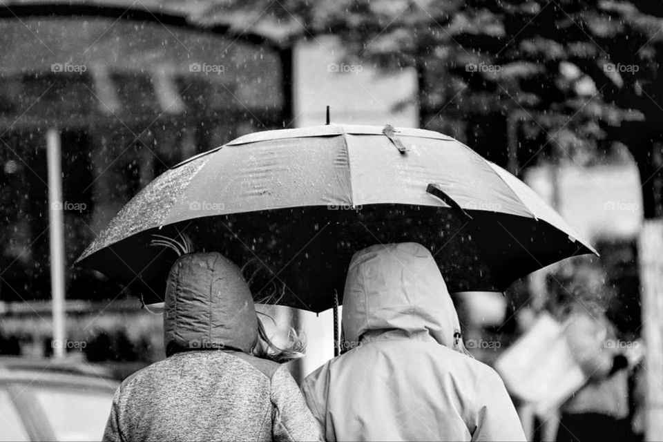 Black and white photo of two women under an umbrella in the rain