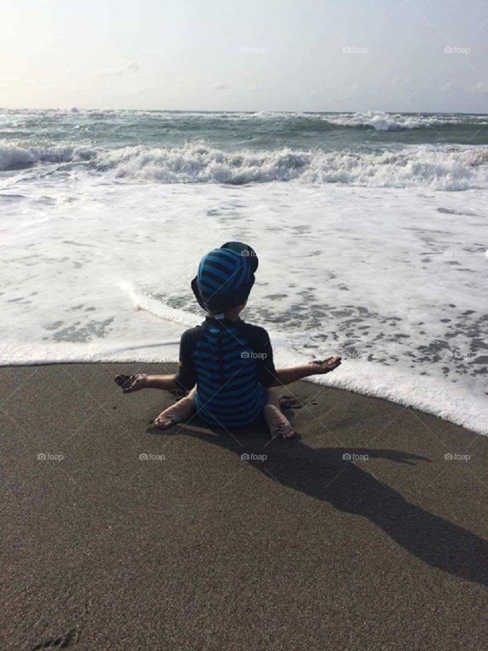 A kid meditating by the sea