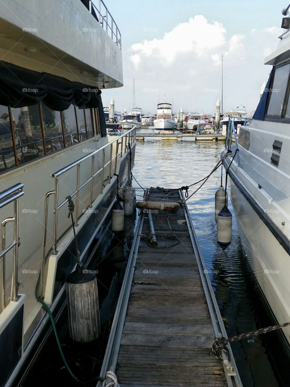 Side by side . Two boats anchored side by side with a shared boarding platform between them.