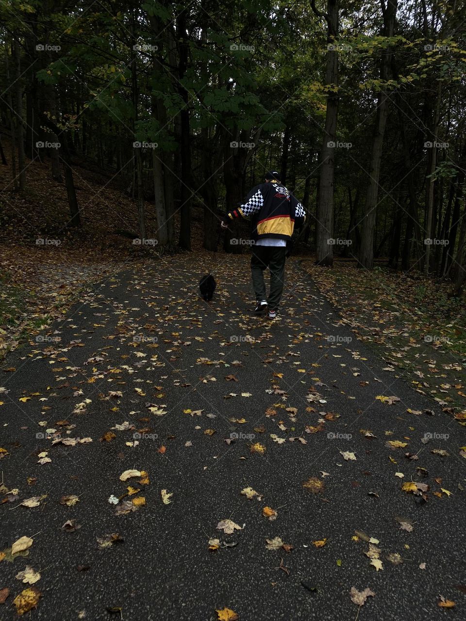 Man with dog walking down a trail in the fall