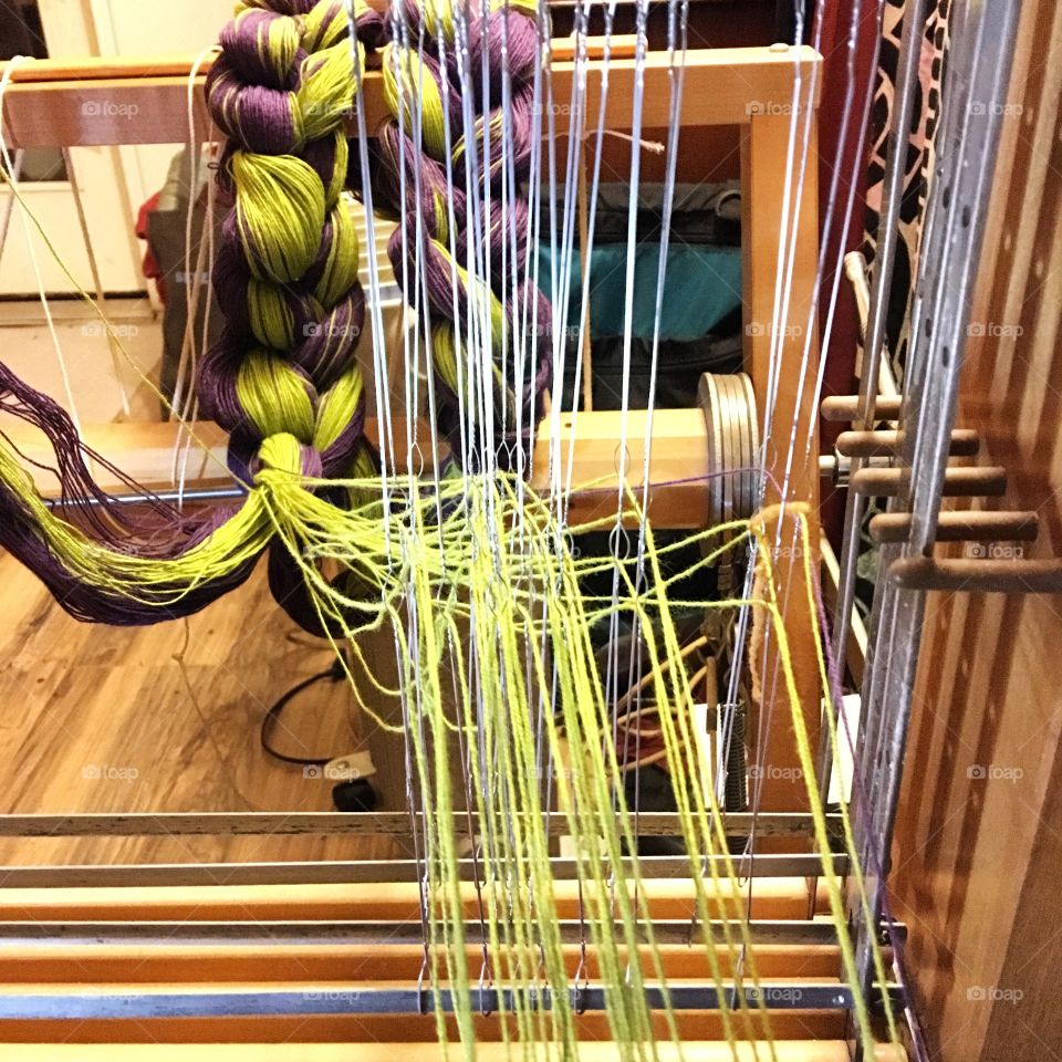 Warping a floor loom with purple and green yarn. 
