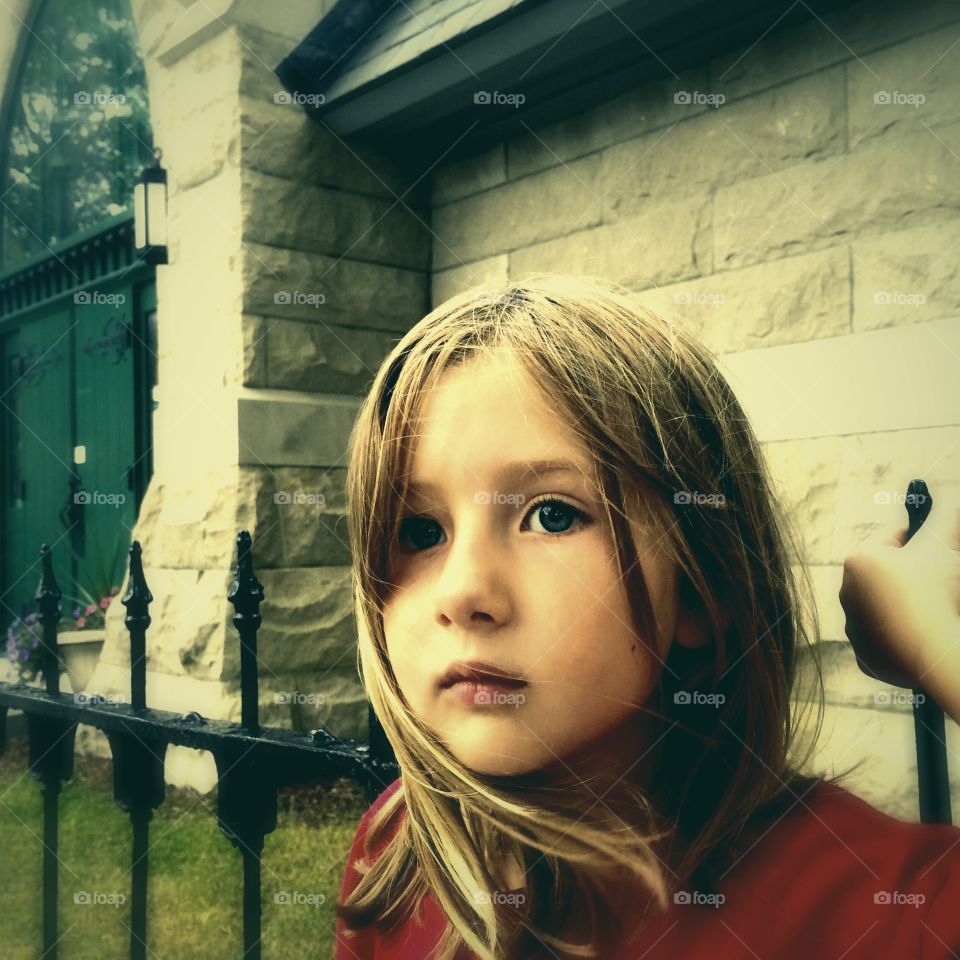 Little girl standing against building wall