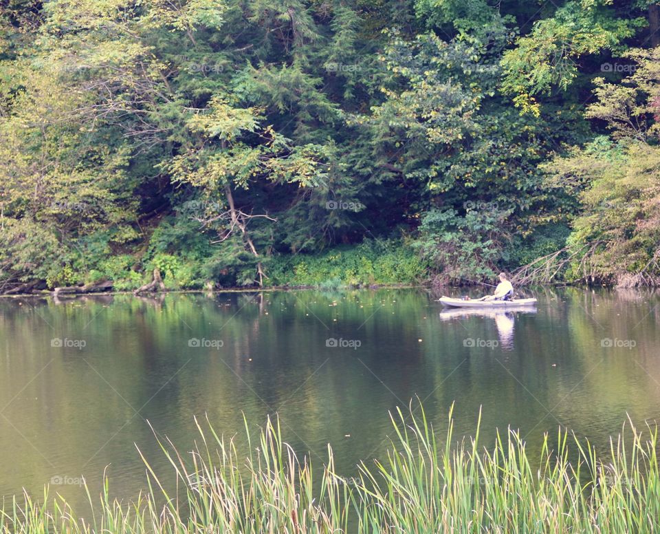 Person in a canoe on a lake with trees reflecting into the water