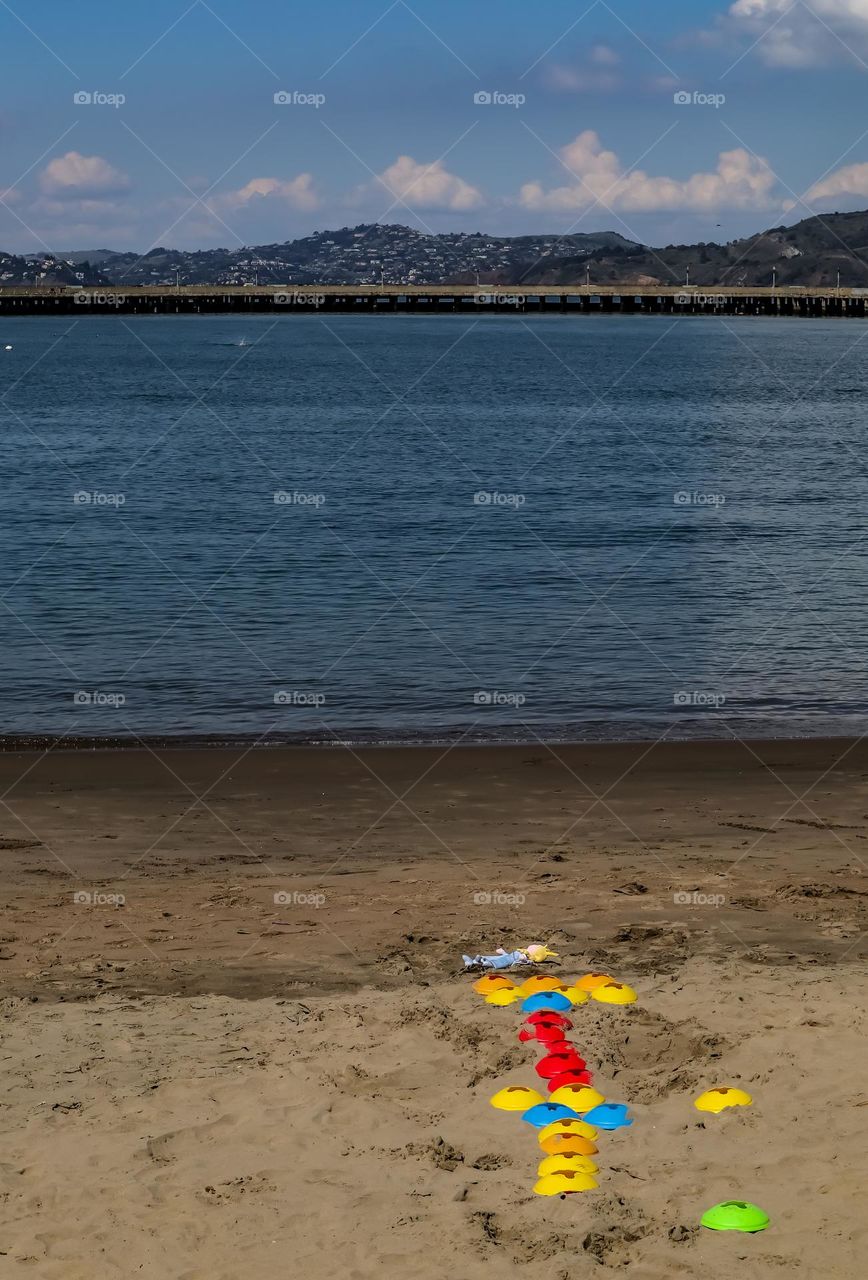 Children’s toys and a doll left abandoned on the beach at Aquatic Park in San Francisco California just waiting for someone to return to play with them