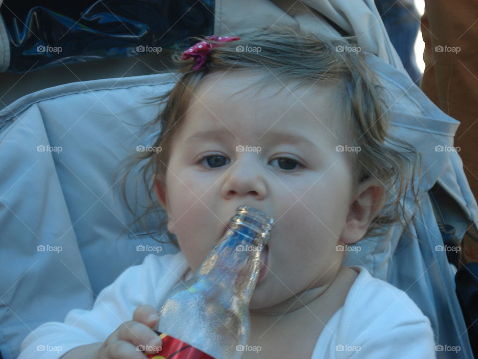 Cute baby girl with a bottle of coca cola