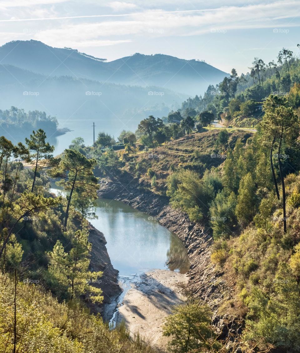 A view of the river and mountains in the distance on a misty morning at Valbom