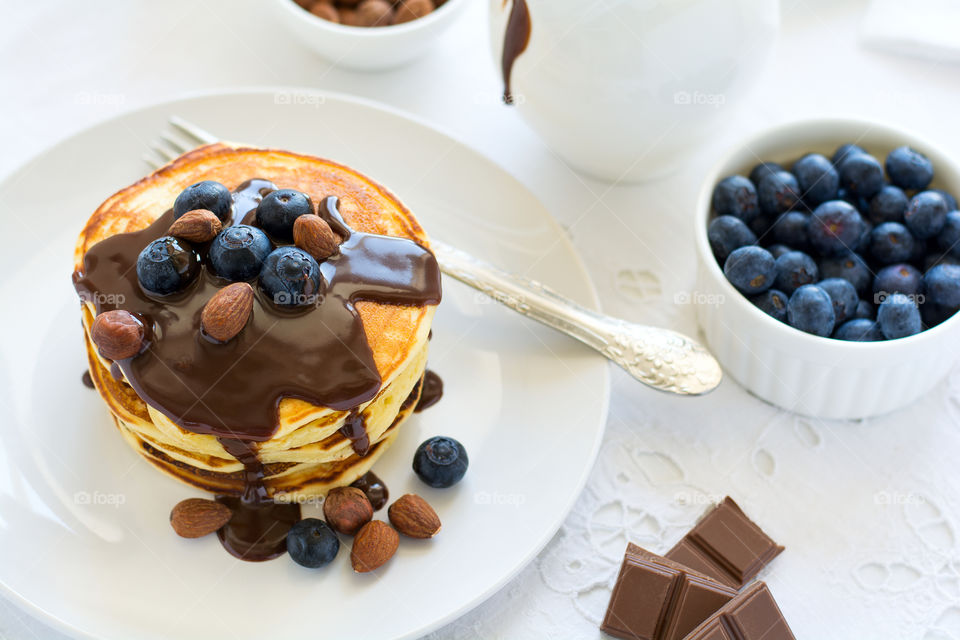 Stack of pancakes with chocolate sauce, blueberry and nuts. Healthy breakfast concept