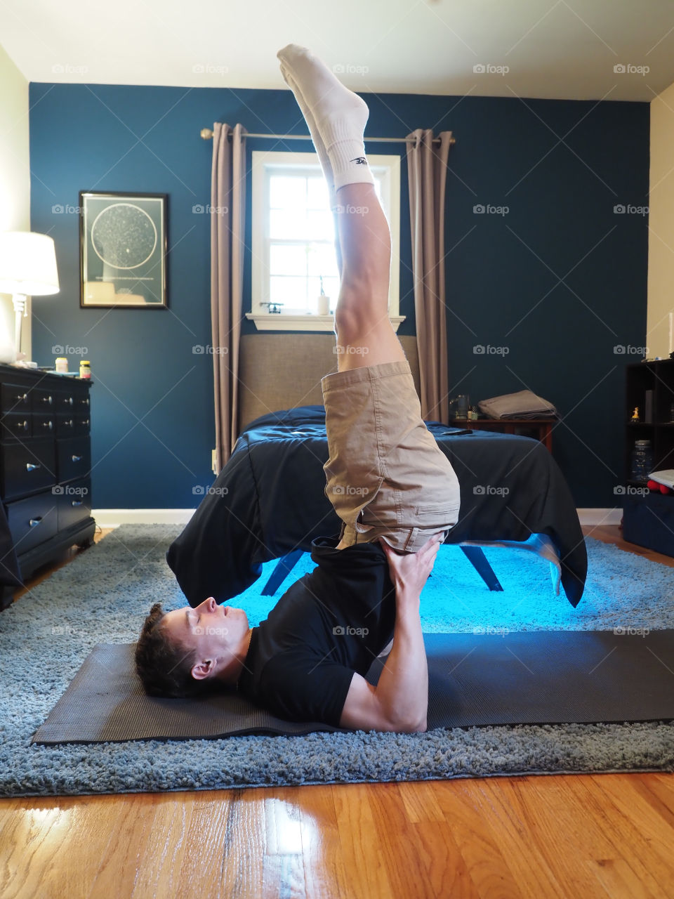 Young man performing yoga at home indoors