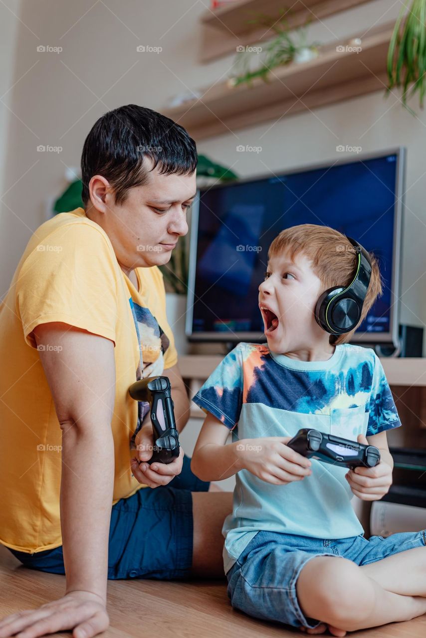 Child red-haired boy plays a video game with his father