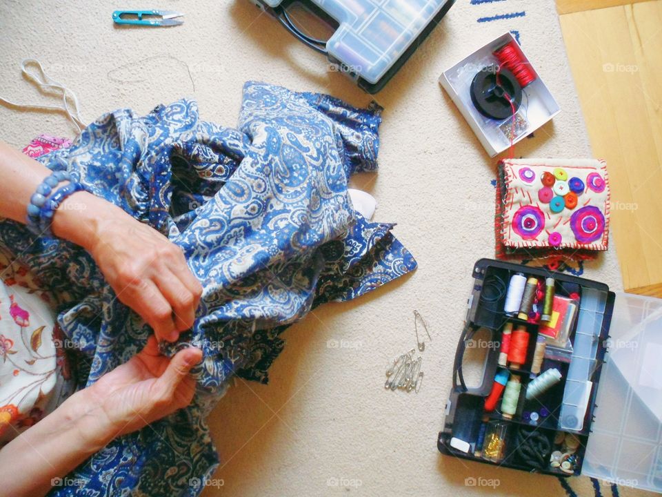 woman sews clothes in hand