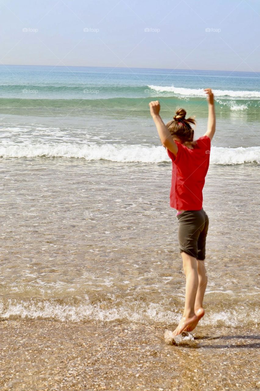 Girl jump above the little waves at the sea shore 