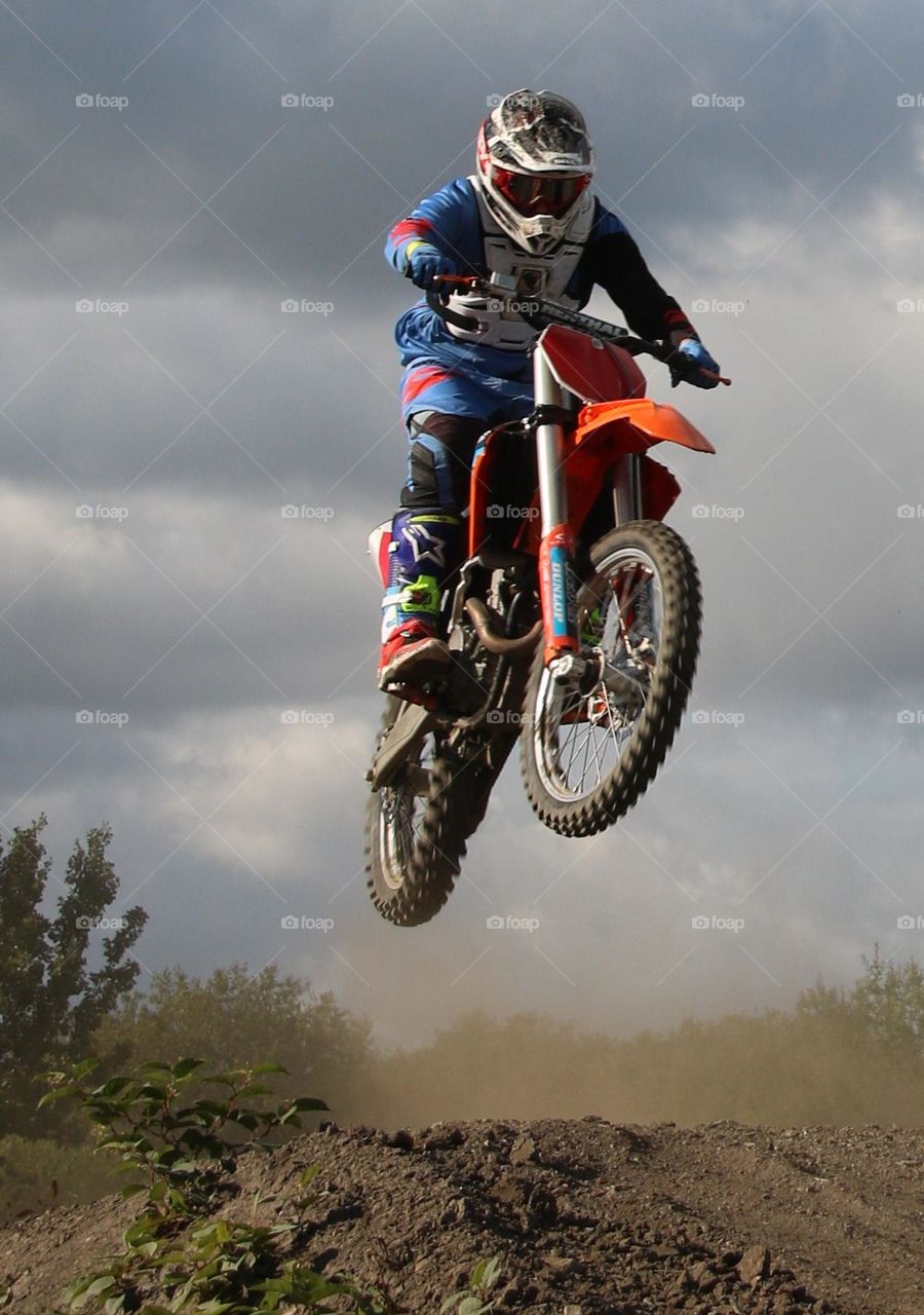 Motor cross rider living dangerously having fun and jumping over a small hill 