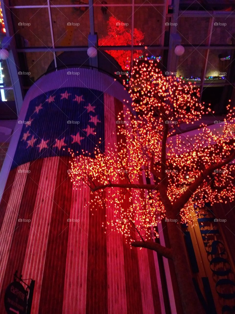 Lighted tree next to a silo with painted flag