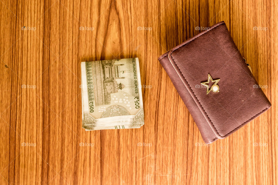 Indian five hundred (500) rupee cash note in brown color wallet leather purse on a wooden table. Business finance economy concept. High angel view with copy space room for text on bottom side of image