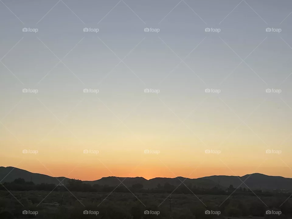 An orange sunset with mountains below.