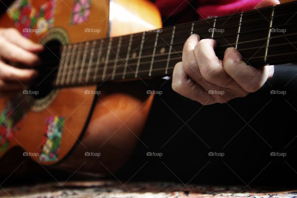 Close up of fingers playing an acoustic guitar