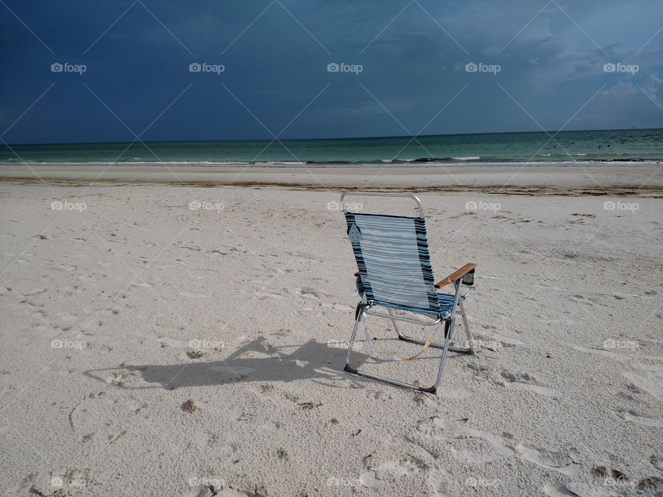 Beach chair by ocean shore.