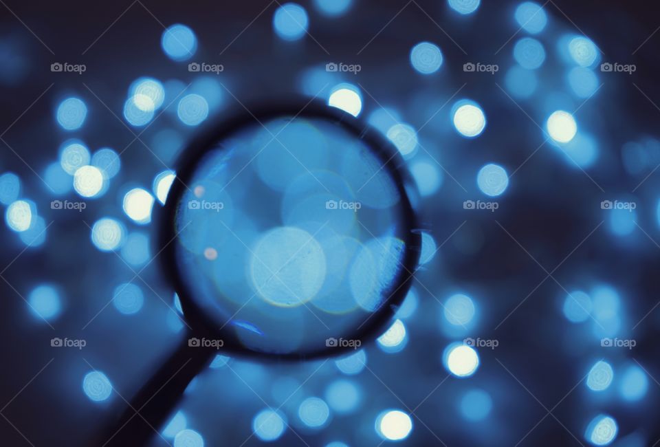 Blue color magnifying glass light flash night illuminated dark background close-up celebration