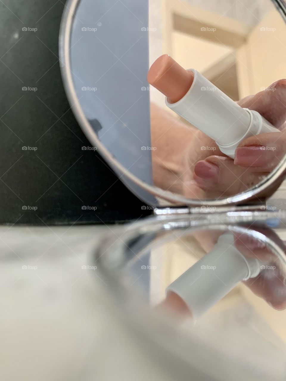 Close-up reflection of a hand holding a lipstick
