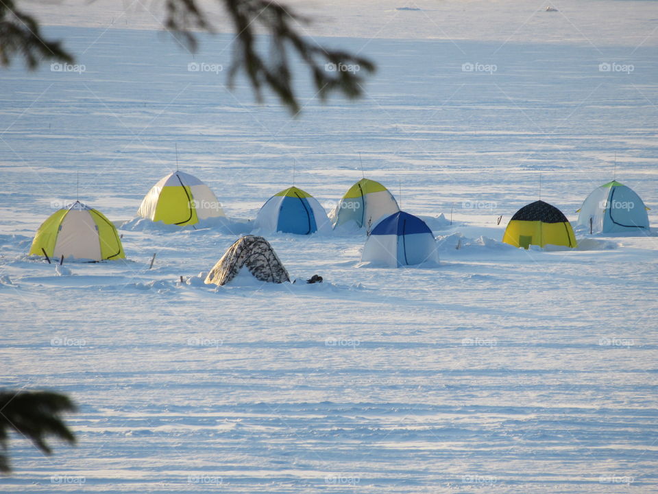 tents of fishermen on the ice in the pond in the Urals in Russia