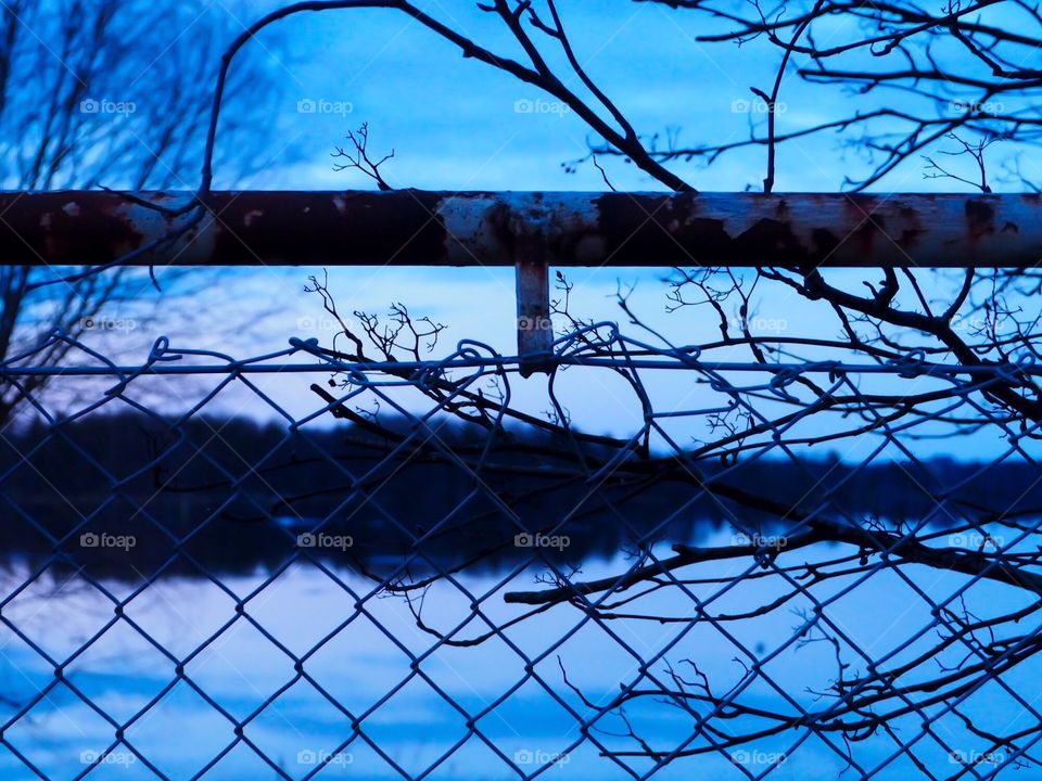 Beautiful landscape is visible through the fence. Branches and rust brings nice touch to this picture.
