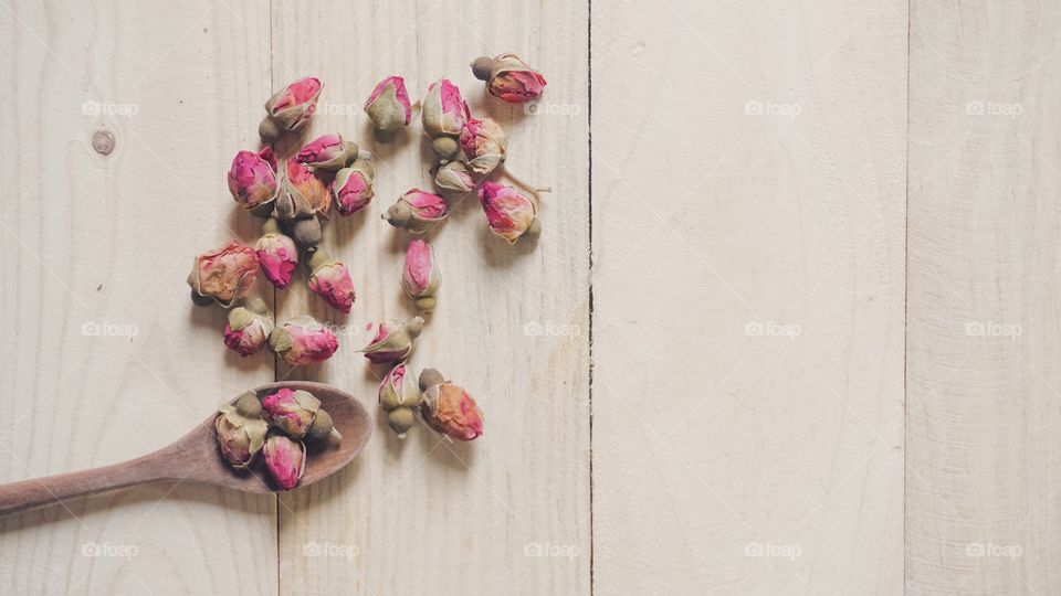 dried rose bud tea with wooden spoon on wooden table 