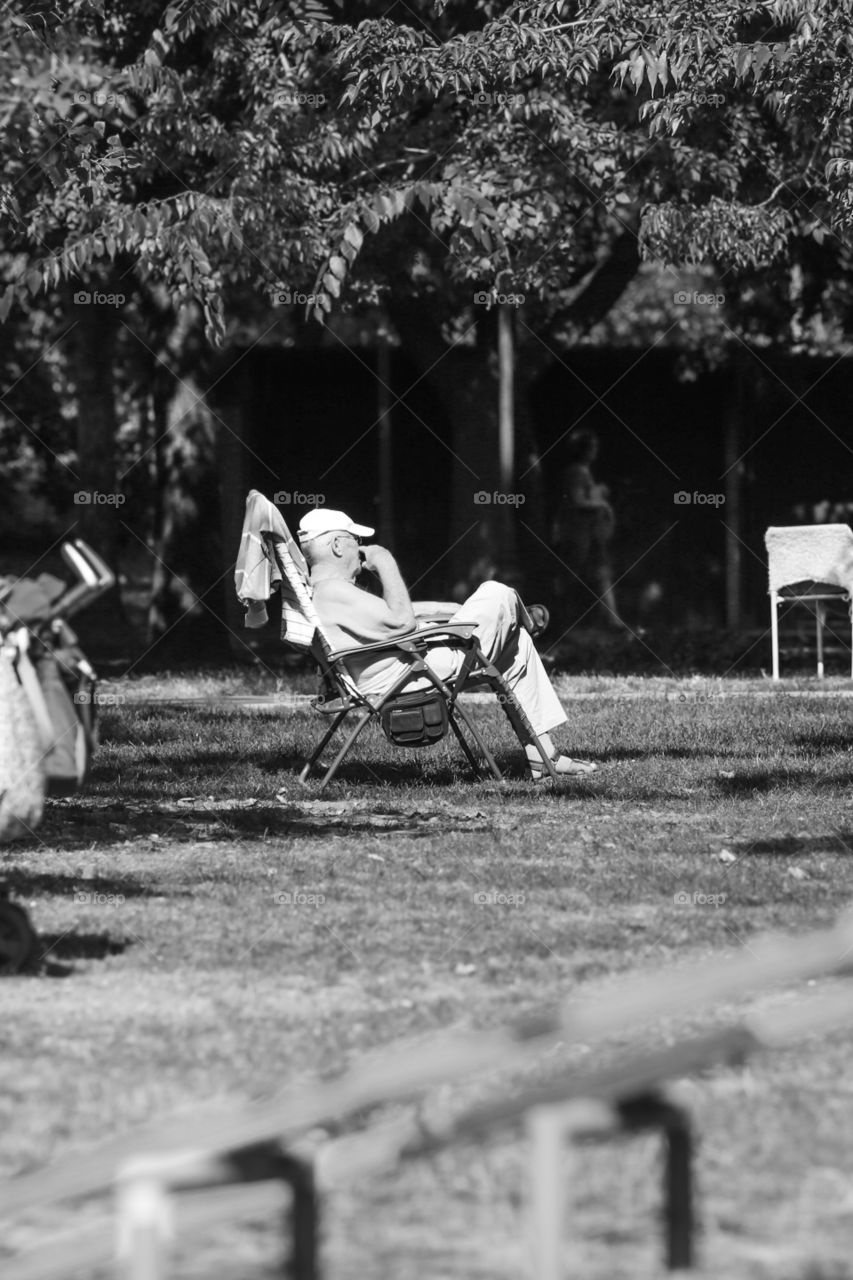 Elder man enjoying sunny day in his chair at the river beach